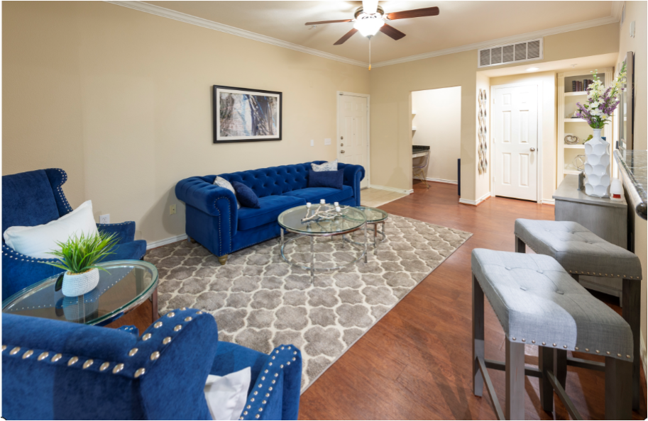 a living room with blue furniture and a ceiling fan